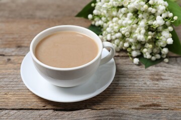 Bouquet of beautiful lily-of-the-valley flowers and coffee on wooden background, closeup