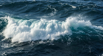 Fototapeta premium Ocean wave cresting and breaking with frothy white foam on a dark blue sea