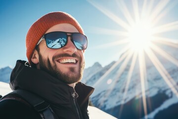 Bright winter day in the mountains with a smiling man wearing sunglasses and a beanie enjoying the sun and snow on a scenic hiking adventure