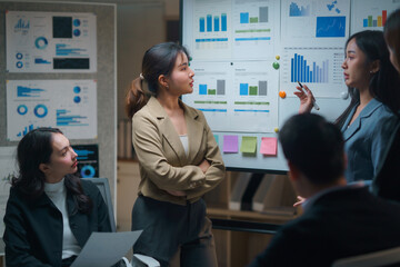 Business team engaged in analyzing financial charts on a whiteboard during a collaborative meeting in a contemporary office setting