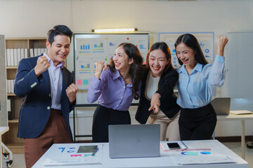 Happy businesspeople celebrating successful teamwork and good results looking at laptop in the office