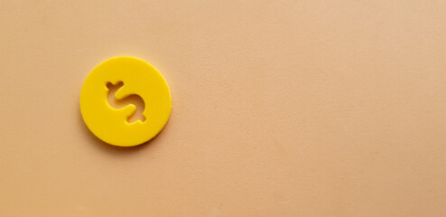 yellow coin with dollar sign and beige background conceptual photo
