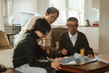 Grandfather, son, and grandson sitting at a table talking while looking at a map