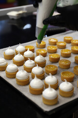 repostero profesional rellenando con una manga pastelera tartaletas de hojaldre y crema pastelera