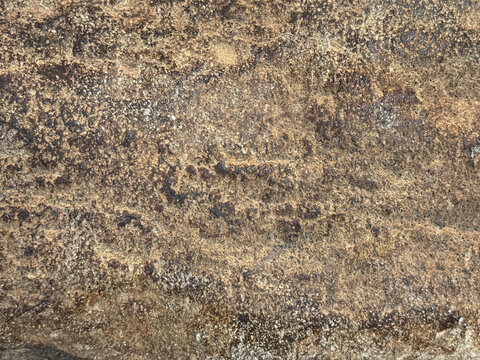 Close up of rusty and weathered granite stone texture, suitable for outdoor and exterior material. Oxidized, and decomposed in golden bronze color. Seamless stone background texture.