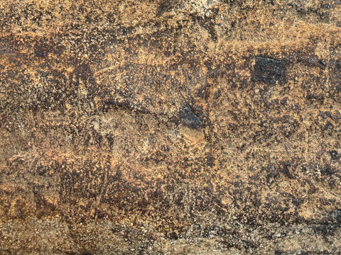 Close up of rusty and weathered granite stone texture, suitable for outdoor and exterior material. Oxidized, and decomposed in golden bronze color. Seamless stone background texture.