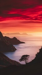 Dramatic sunset over the ocean, silhouetted mountains and a lone tree. The vibrant red and orange hues paint a breathtaking scene