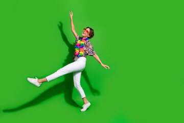 Full length photo of overjoyed woman dressed print blouse in sunglass dancing look empty space sale isolated on green color background