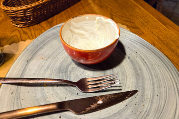 Finished Meal Setting with Empty Dessert Bowl and Utensils on Wooden Table