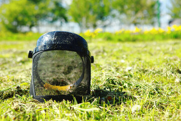The face mask lies on the mown grass. Mowing the grass
