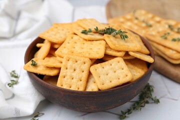 Tasty salty crackers and thyme on white table, closeup
