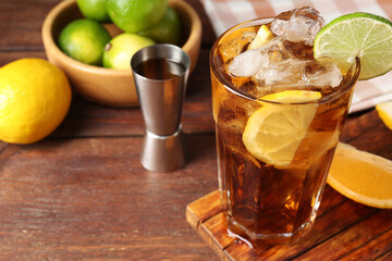 Refreshing Cuba libre cocktail and ingredients on wooden table, closeup