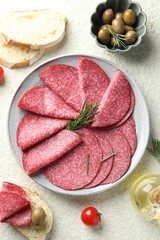 Slices of delicious sausage with rosemary served on white textured table, flat lay