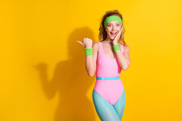 Young woman in retro workout attire striking a playful pose against a vibrant yellow background...