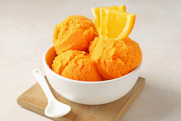 Tasty orange sorbet, fresh fruit and spoon on light table, closeup