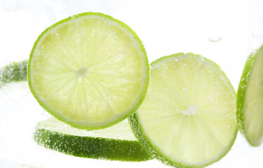 Refreshing soda water with slices of lime in glass on white background, closeup
