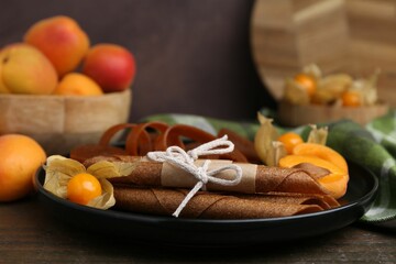 Tasty fruit leather, physalis and apricots on wooden table, closeup