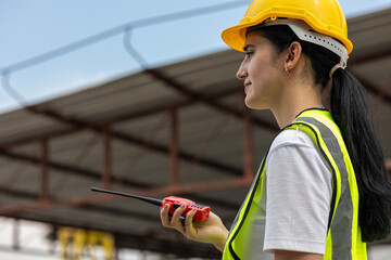 Female civil engineer with walkie talkie stands next to ready made wall or precast boards...
