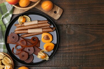 Tasty fruit leather, physalis and apricots on wooden table, flat lay. Space for text