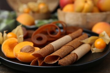 Tasty fruit leather, physalis and apricots on wooden table, closeup