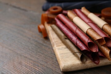 Tasty fruit leather rolls on wooden table, closeup. Space for text