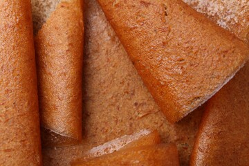 Delicious fruit leather rolls as background, top view