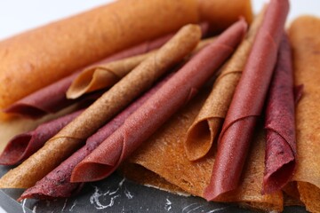 Delicious fruit leather rolls on table, closeup