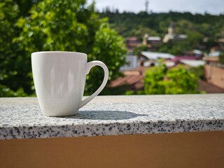 White mug standing on granite surface with cityscape in background