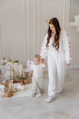 Mother with little son at home against the background of Easter decor of live rabbits, basket, eggs, flowers and willow