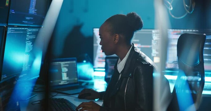 African woman, computer and monitor for cybersecurity at night, code and review with software at office. Person, developer and pc with screen for information technology, programming and protection