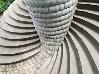 Double spiral staircase winding around a gray stone pillar
