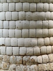 Curved wall showing decaying white paint on rounded bricks