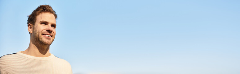 Obraz premium Handsome man strolls along a sunny path, embracing the beauty of a clear day outside