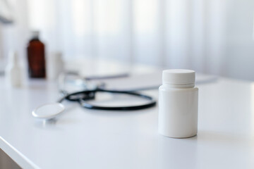 Medical workplace with white plastic pill bottle on white desk, and medical equipment including stethoscope and other medicine bottles blurred in the background, selective focus