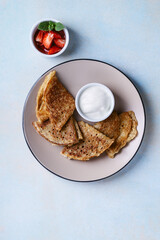 Sweet rye and whole grain crepes with strawberry and sour cream directly above