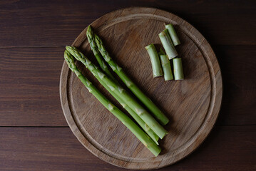 cutting Green Asparagus on wooden cutting board table
