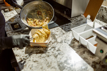 A skilled chef serves creamy pasta in a modern kitchen, showcasing expertise and culinary skills to perfection