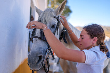 Teenage equestrian preparing horse's tack, adjusting bridle with gentle care, sharing peaceful moment in sunlit stable