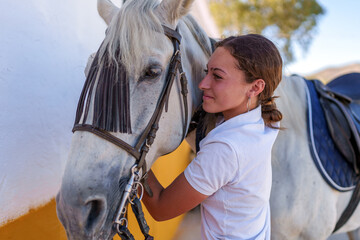 Obraz premium Warmhearted young rider embracing white horse affectionately inside wooden stable before equestrian event
