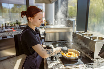 A skilled chef focuses on preparing pasta in a modern kitchen filled with steam and fresh ingredient aromas