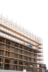 Scaffolding surrounds tall concrete building. Construction site of a modern residential or commercial property. Safety and security in high risk working environment.