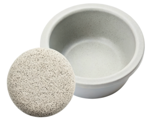 Speckled ceramic bowl with a matching round textured scrubber on a transparent background