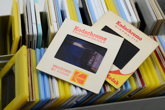 a close-up of a collection of vintage Kodachrome photo slides, primarily 35mm transparencies, stored in a plastic container