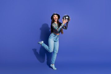 Young woman with a glossy disco ball posing against a vibrant purple background, showcasing her...