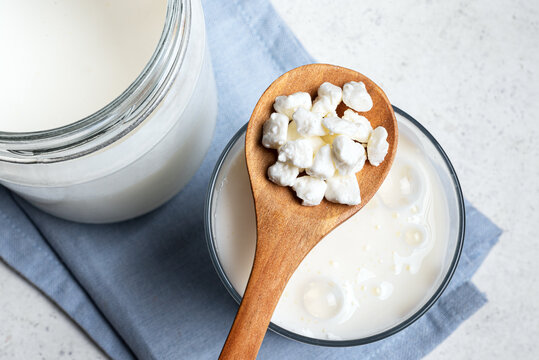 Milk kefir grains on wooden spoon and jar of kefir
