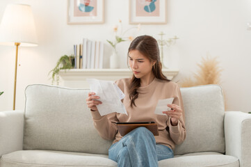 Asian woman feeling unhappy after looking at the bill feels stressed having financial problem, check finances, experiencing lack of money pay for loan, huge taxes, utility rates, get eviction notice