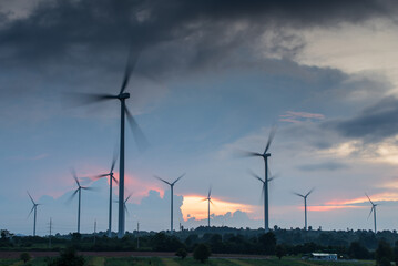 Obraz premium Electricity generating station, Wind turbines power generator in agricultural fields at sunset, Alternative Energy Windmill Farm