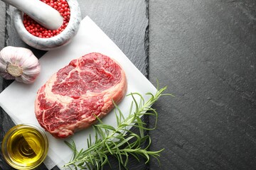 Piece of raw beef meat and spices on black table, flat lay. Space for text