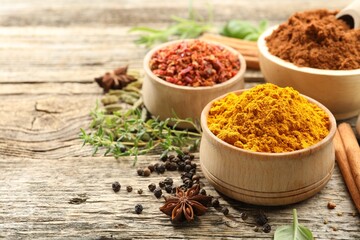 Different aromatic spices on wooden table, closeup. Space for text