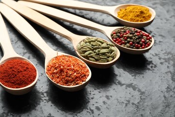 Many different spices in spoons on black table, closeup
